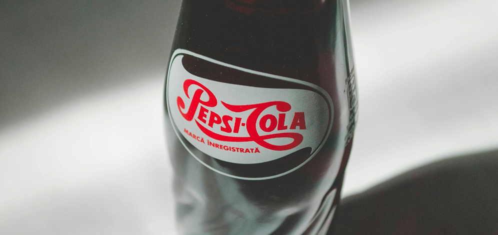 Botella de cristal de Pepsi-Cola fotografiada sobre un fondo oscuro.