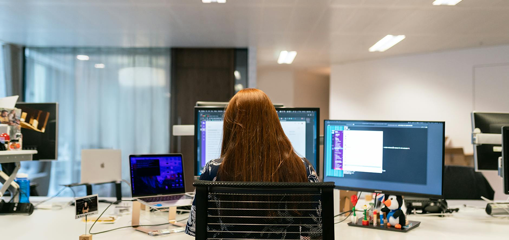 Persona trabajando ante dos monitores en una oficina.
